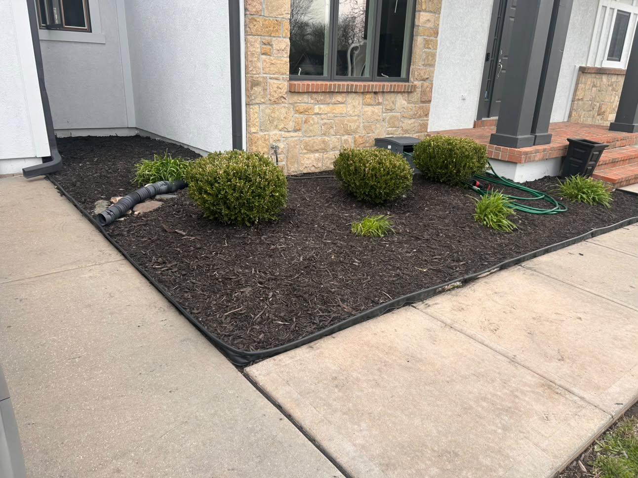 Dark mulch bed with shrubs along the front of a home
